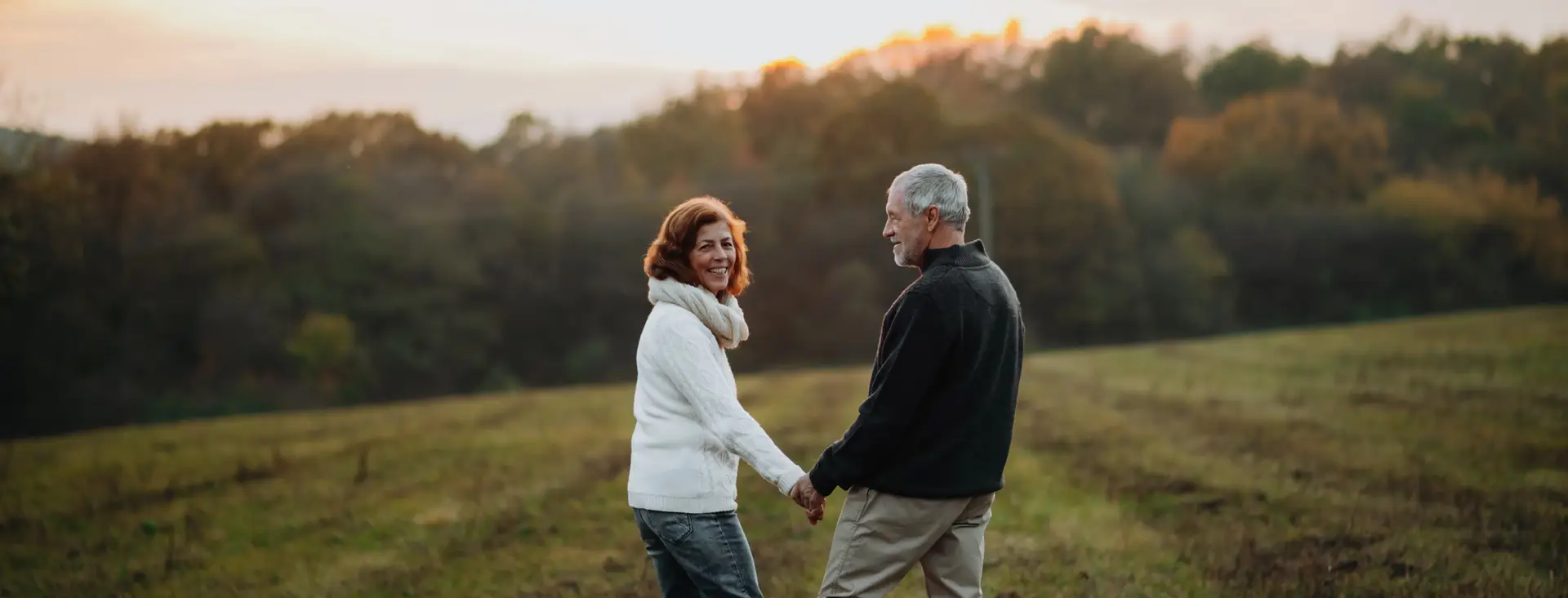 Older couple holding hands in field