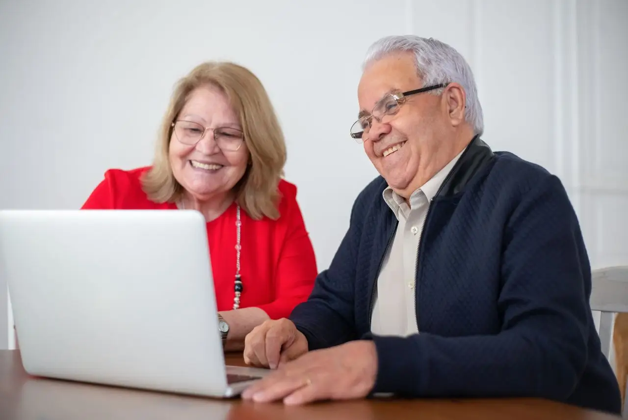 Smiling older couple looking at a laptop together at their kitchen table